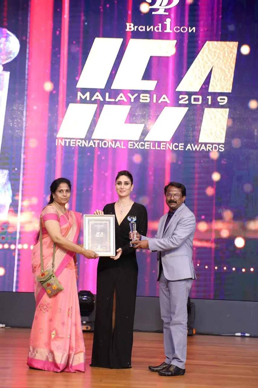Two people from Oxymedpro on stage at the International Excellence Awards, Malaysia 2019, with a certificate and a trophy.