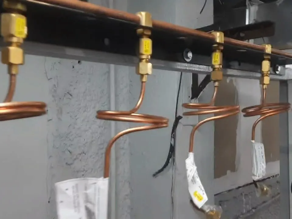 Coiled copper tails with brass fittings hanging from a manifold header.